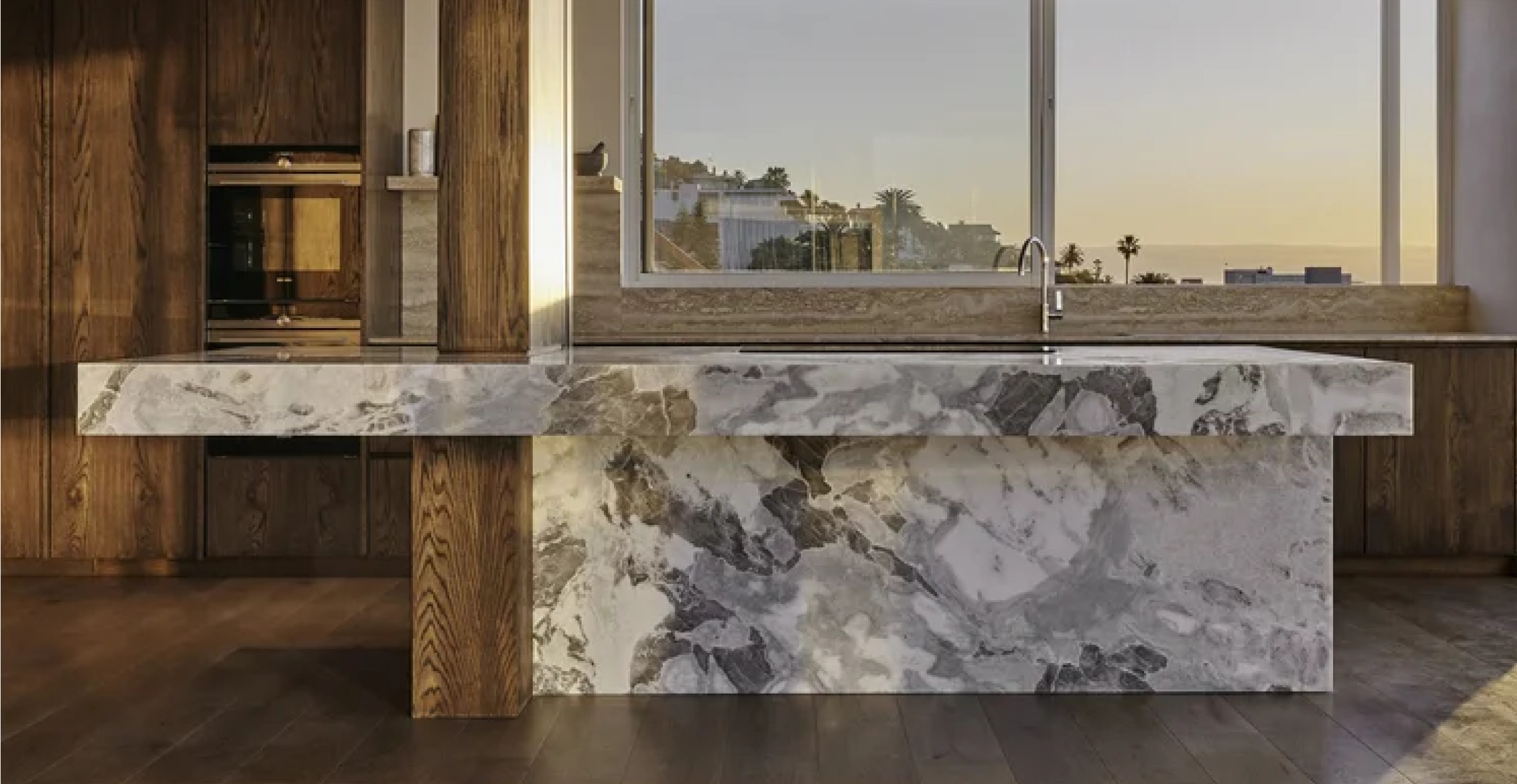 Large white marble slab island in kitchen with medium wood tone cabinets
