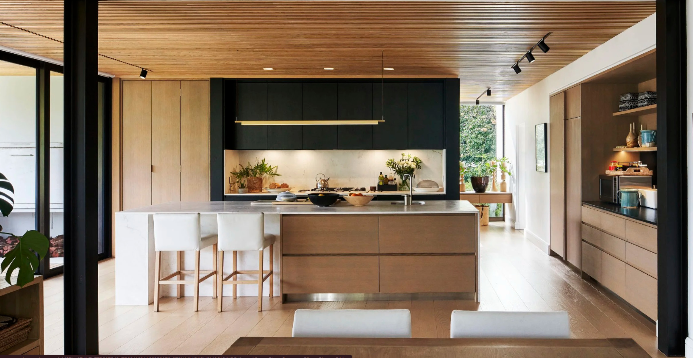 Warm wooden and black modern kitchen with wood pannelled ceiling and large kitchen island