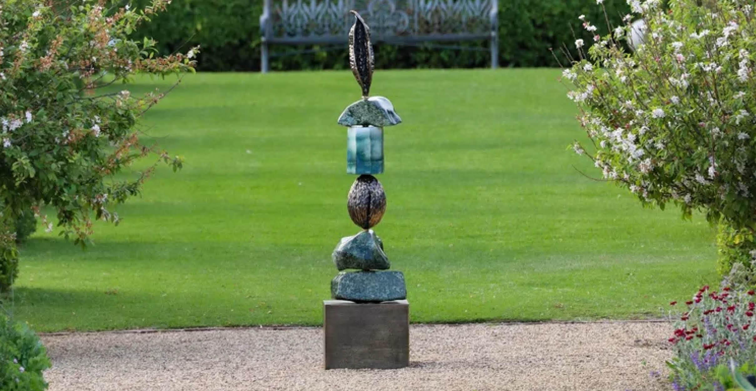 Blue and silver sculpture in a manicured garden