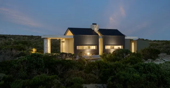 Modern stone clad home with black metal roof and cladding in rural west coast